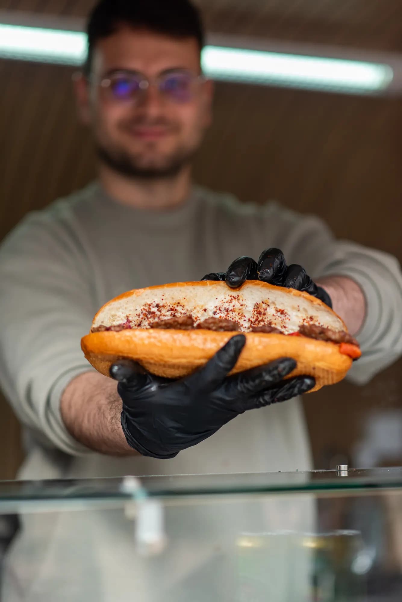Ein volles Köfte-Brot, mit schwarzen Handschuhen aus dem Truck gereicht